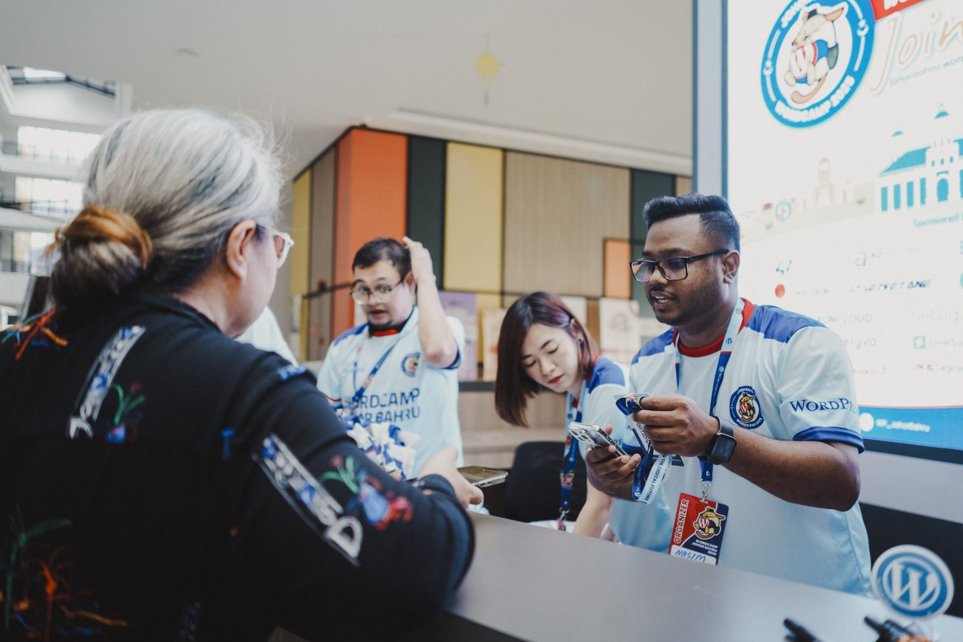 Nasim miah volunteering at wordcamp johor bahru 2025 attendance check-in